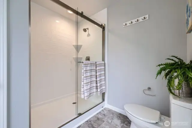 Enjoy the sleek walk-in shower with floor-to-ceiling subway tile, sliding glass doors, and upscale brushed nickel fixtures.