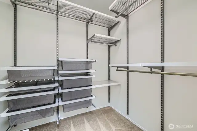 Maximize organization in the primary walk-in closet, featuring built-in shelving, drawers, and hanging space for seamless storage.