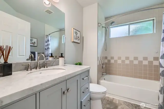 The upstairs full bath includes an updated quartz-top vanity, tile surround, and a combination tub/shower for flexible functionality.