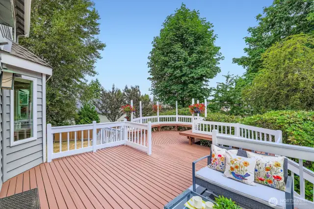 Enjoy lush views and privacy from the upper-level deck, framed by flowering plant basket hangers and towering evergreens.