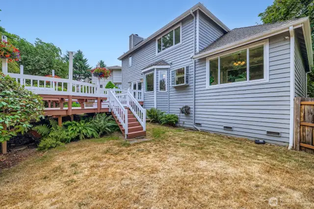 Backyard perspective shows the home’s full rear elevation, with tiered deck access and northwest ferns.