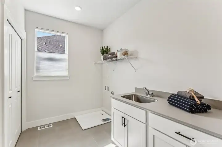 Pic is of model- Upstairs laundry room w/quartz counter, sink and cabs.  Large storage/linen closet and operable window.