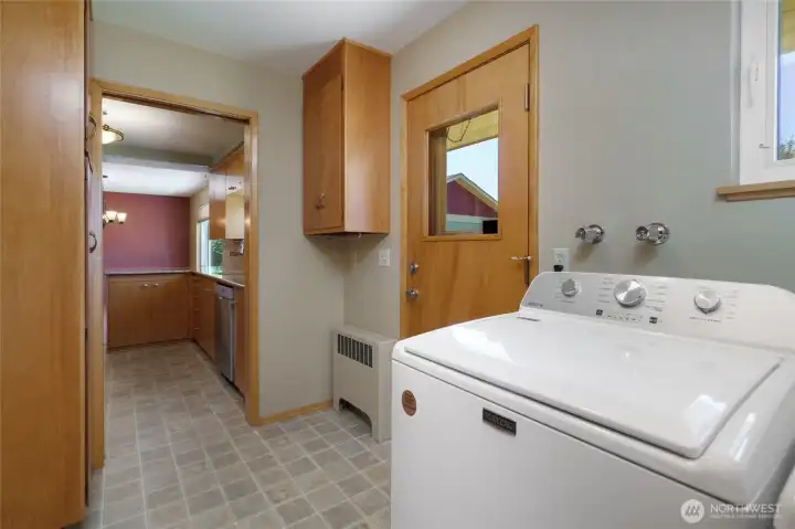 Laundry room view towards kitchen with back door to the right of the photo.