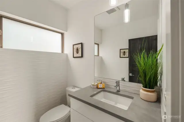 Main floor powder room with designer tile wall feature and floating vanity.