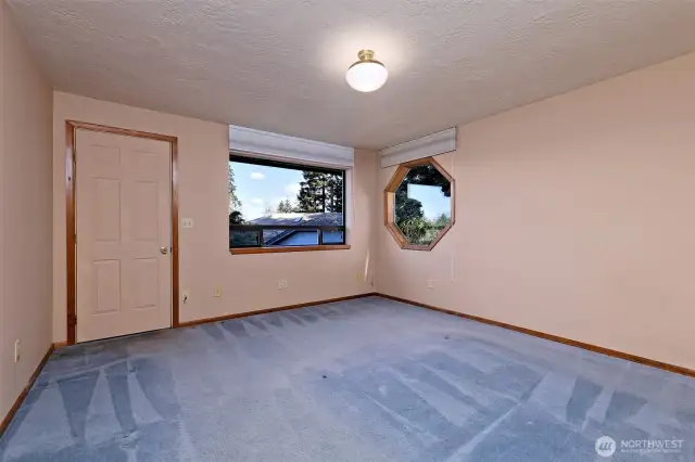 The Primary bedroom with a cute octagonal window, and a door leading out to the front deck.