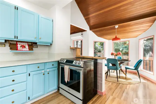 The cheerful kitchen has tall ceilings and is open to the dining room. The induction stove is a new Bespoke 6.3 cu. ft. Smart Rapid Heat Induction Range with Air Fryer + True Convection Oven, White Glass Finish (2023).