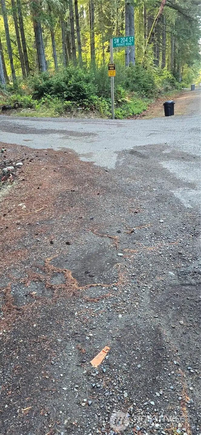 Southwest corner of the lot at the corner of SW 204th Street and Westside Hwy. The lot is 300 feet wide x 300 feet deep (perfect square that is 2.07 acres).  Gorgeous fully wooded lot that provides privacy and natural beauty.