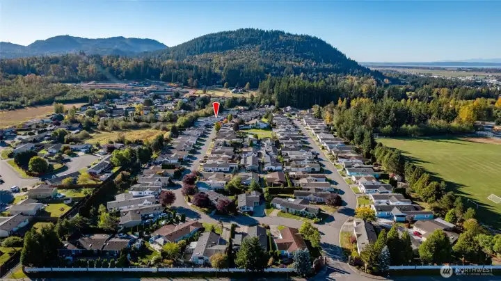 Red arrow at left shows location of #97, while the green space in the center of the photo is the grassy common area outside the clubhouse where the picnic and patio area, shuffleboard, and horse shoes are located.  The gated entry is at bottom right.