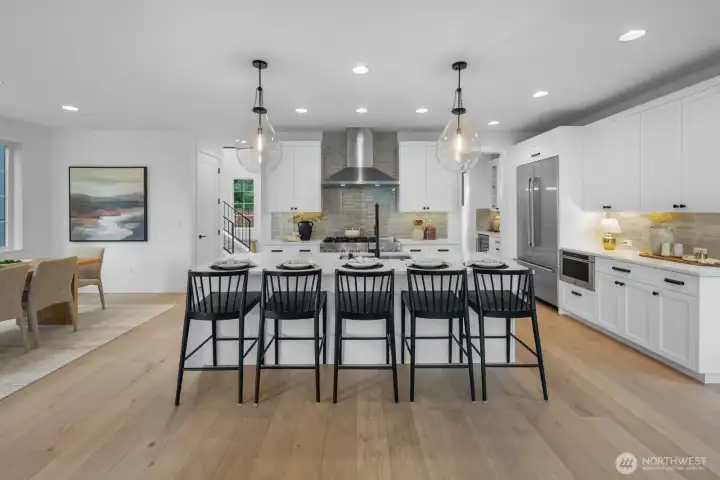 Gourmet kitchen featuring an oversized waterfall island with seating for five, professional-grade appliances, custom cabinetry, and designer tile backsplash. A true centerpiece for the home.