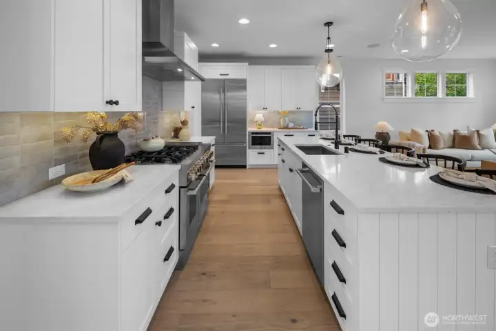 Expansive gourmet kitchen featuring dual ovens, oversized island with seating, designer lighting, and abundant storage. Elegant and highly functional for modern living.