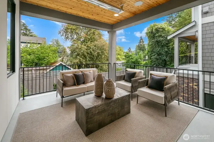 Covered outdoor living room with wood-clad ceiling, recessed lighting, and private treetop views. A perfect extension of the home for year-round enjoyment.