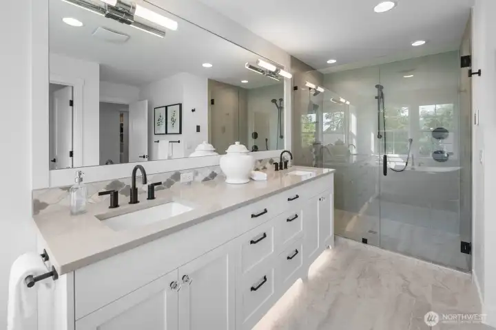 Spacious en-suite bath featuring a glass-enclosed shower with dual shower heads, custom tile work, and sleek modern fixtures.