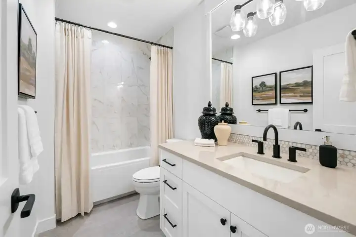 Well-appointed full bath with quartz vanity, designer tile surround, and modern fixtures. Stylish and functional for everyday living.