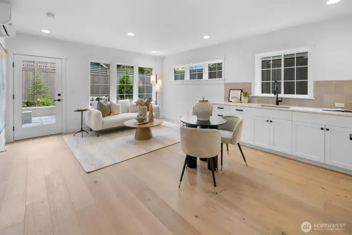 Light-filled lower-level living space with wide-plank hardwoods, kitchenette, and direct access to the private patio and backyard.