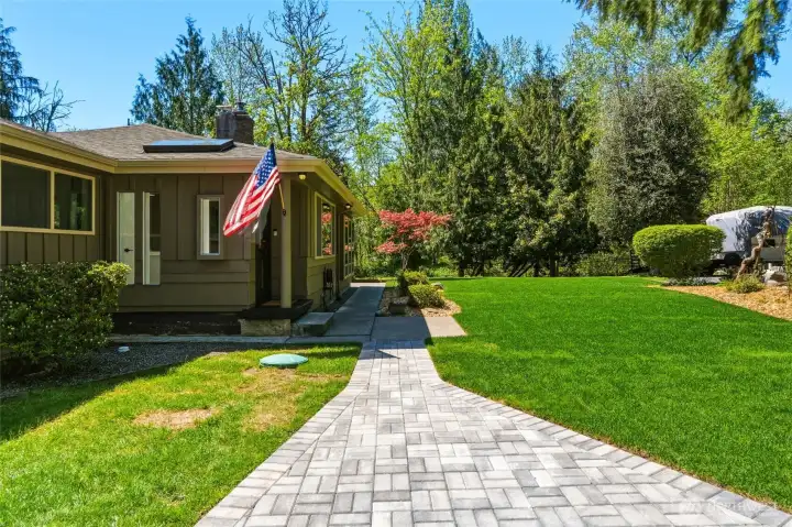 Welcoming front walkway and entry with lush lawn, mature trees, and inviting outdoor space ideal for enjoying nature.