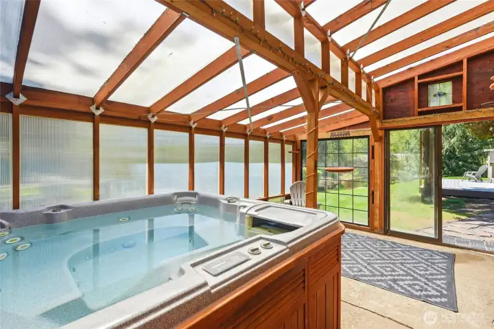 Dedicated indoor spa retreat featuring hot tub, vaulted wood ceilings, and panoramic outdoor views.