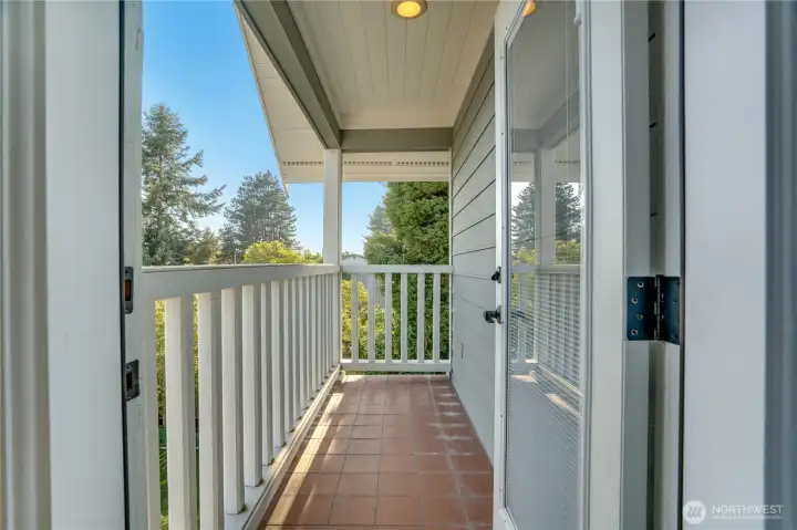 Step out of the primary suite onto your own private covered balcony. Treetops, blue sky, coffee.