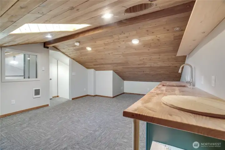 14 × 26 finished loft. Interior window to the shop below. Cadet heat. Butcher block counter. Bathroom through that door. Completely self-contained.
