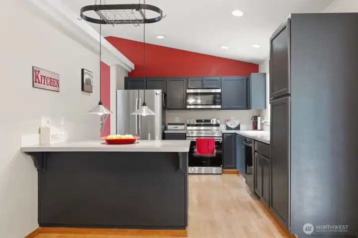 The gourmet kitchen with its oval ceiling pot rack, stainless steel appliances and peninsula dining bar opens right into the dining room.