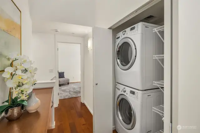 Laundry and linens storage in hallway between primary and secondary bedrooms.