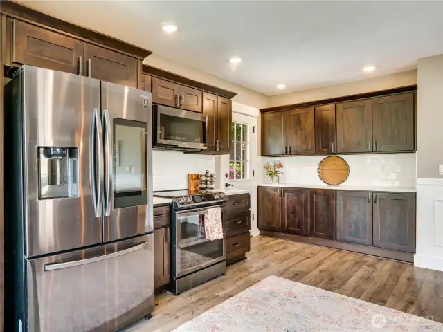 The cabinetry offers additional storage in the kitchen, complemented by a small pantry located in the hallway. Note the luxury vinyl flooring, which is ideal for handling spills and messes commonly happening in the kitchen.