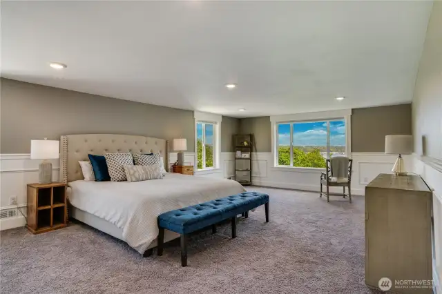 The expansive primary bedroom further highlights the breathtaking views. With its generous proportions, this sophisticated space offers many possibilities. Additionally, there are two walk-in closets not yet pictured. Take note of the elegant wainscoting and chair rail details as well.