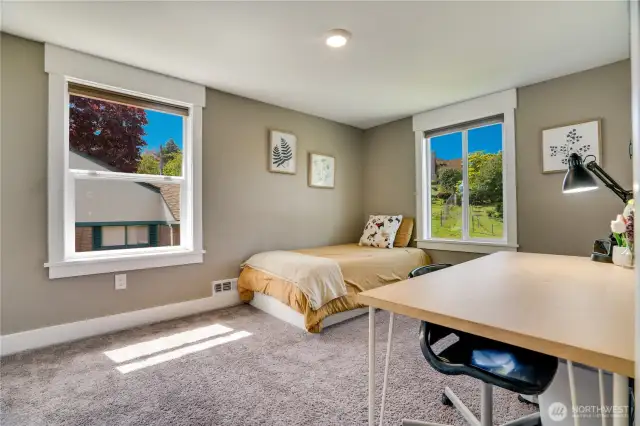 The fourth upstairs bedroom features two bright windows, built-in storage cabinets with drawers, and a spacious closet.