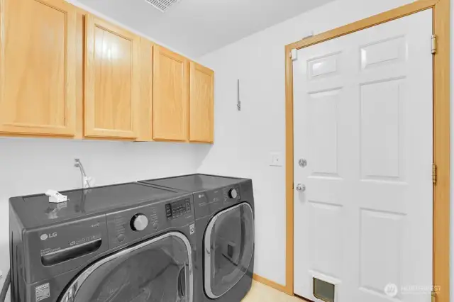 Main floor laundry space room with new washer and dryer. Door is access to the oversized 3-car garage.