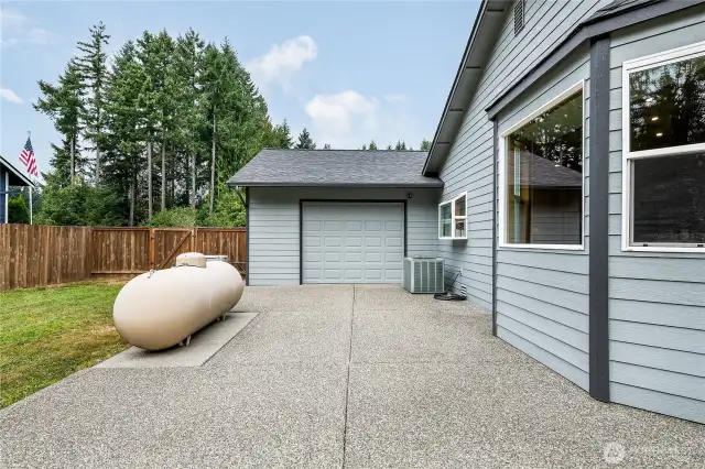 View of pass-through garage on the back of the house. The propane tank (leased) is on the left. Heat pump is on the right under the garden window.
