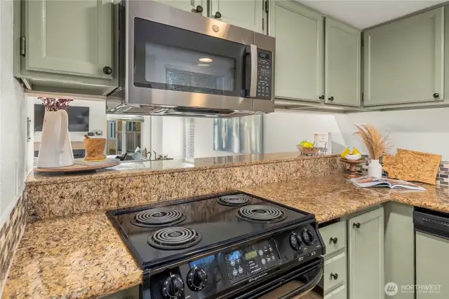 Newer stove and microwave encased in granite counters.