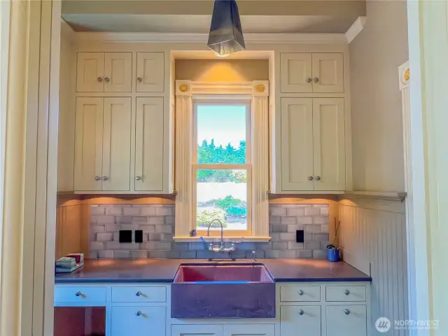 Lovely soapstone sink, cabinetry and lighting in the mudroom. Convenient half bath with pocket door to the right.