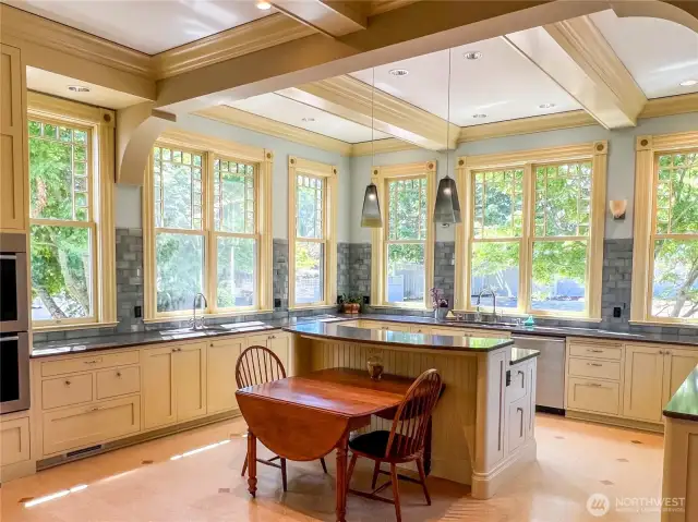 Light-filled eat-in kitchen with a plethora of cabinetry, counter space and two sinks.
