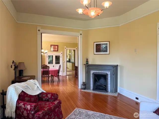 Living room with its own fireplace, opening with pocket doors, into the dining room and kitchen beyond.