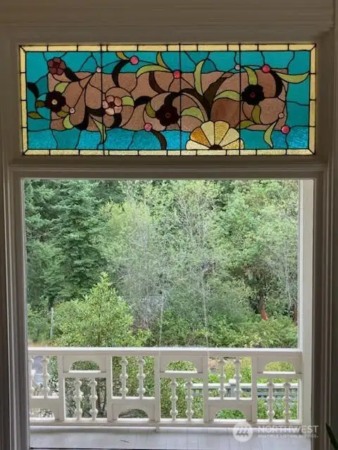 Closeup of colorful stained glass and ornamental railing that beautifies the covered porch and outdoor stairways.