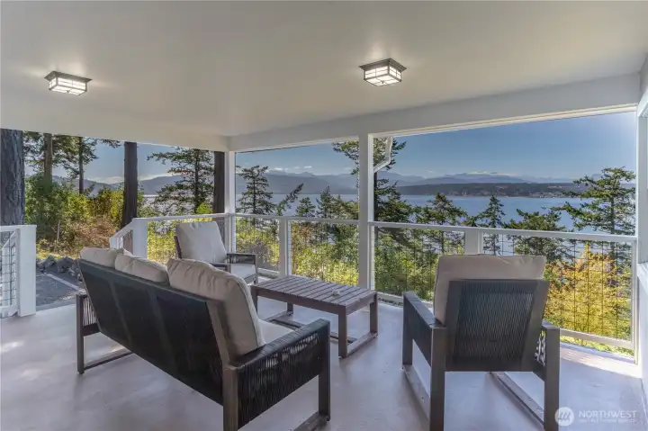 Spacious covered main floor deck with stunning water and mountain views—perfect for enjoying breathtaking sunsets.
