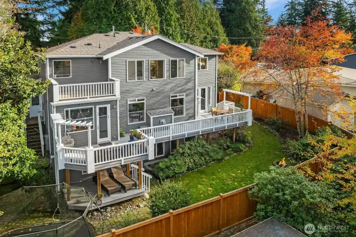 View of the back of the house with entertainment deck with sunset views, fully fenced yard and room for a trampoline!