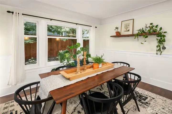 Dining room with wall of windows looks out to lush greenery.