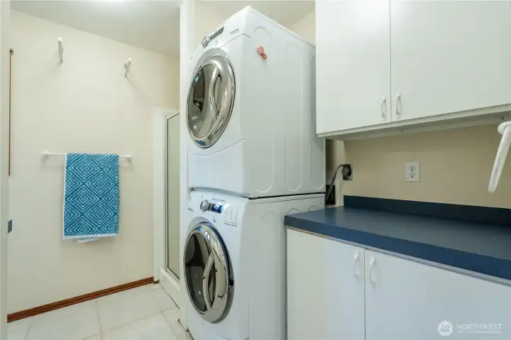 Laundry/Bath room with stackable washer and dryer sits next to shower.
