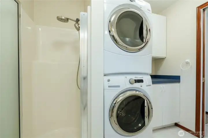 Laundry/Bath Shower next to stackable washer and dryer.