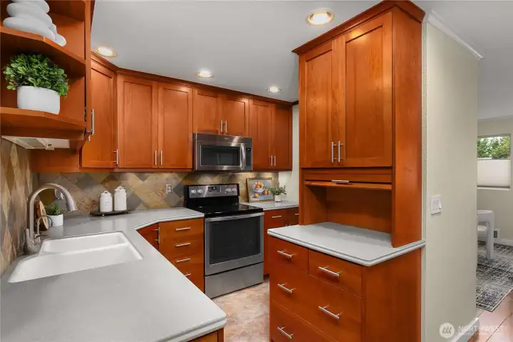 Updated kitchen featuring wood cabinetry, tiled backsplash, and stainless steel appliances