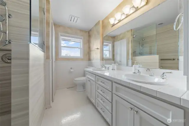 Elegant bathroom with double sinks, extra-large mirror and window keeping this room light and bright.