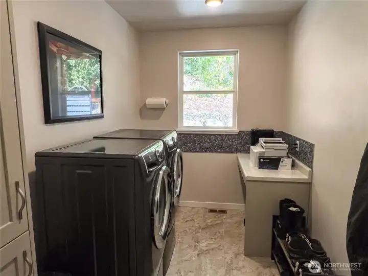 Good size utility room with front load appliances, storage cabinets and countertop that could double as a desk.