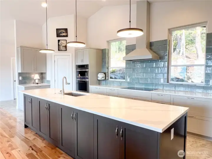 Plenty of cabinets, counters, lighting, large windows, tilework and a walk-in pantry enhance the kitchen environment.