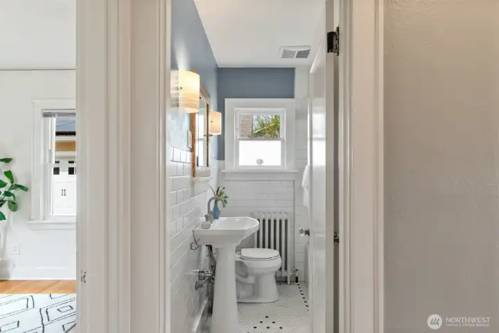 Main floor full bathroom with hex tile floor and tile wainscoting