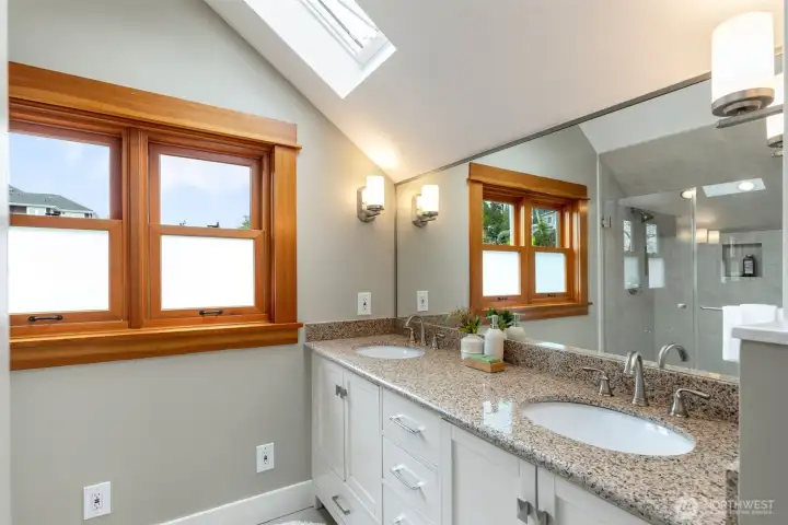 Spacious upstairs bathroom filled with natural light from windows and skylight