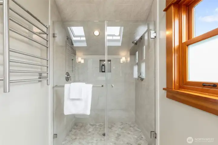 The bathroom has extensive tile work and heated towel rack