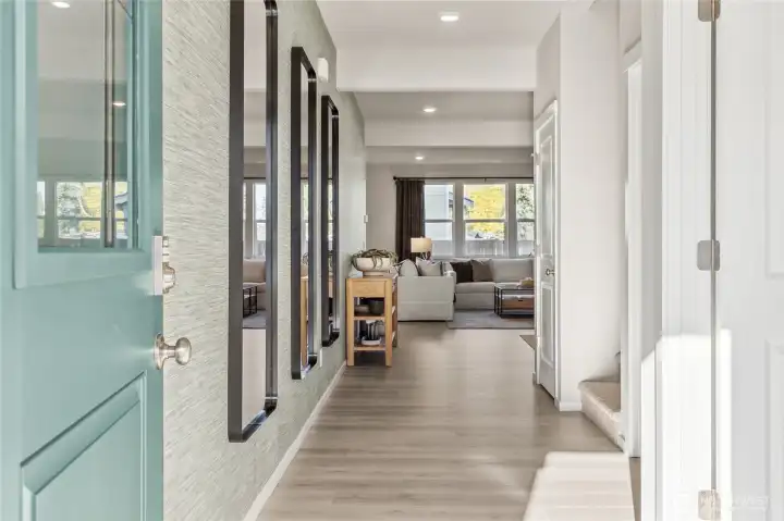 Welcoming entryway showcasing the colorful front door, open foyer, and view into the main living area with luxury laminatel plank flooring. For illustration purposes and some variation may apply.