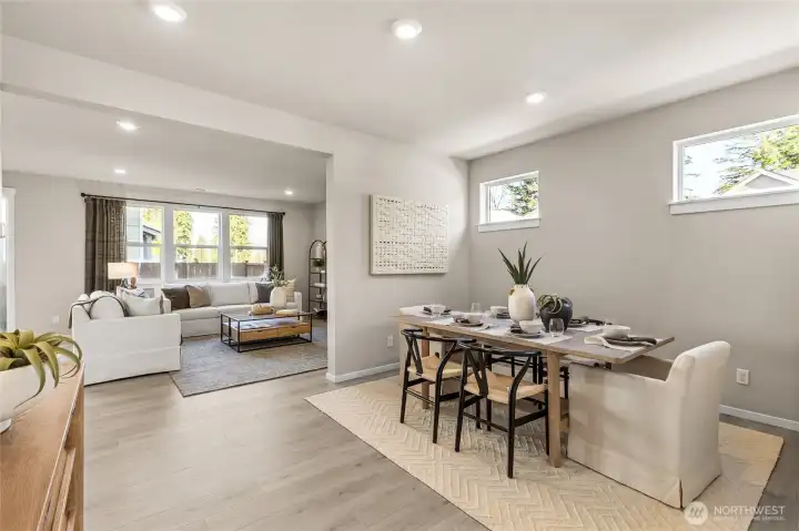 Open-concept dining and living area with abundant natural light, luxury laminate plank flooring, and seamless flow between spaces. Photos are representative only and may display different color package and/or upgrades.