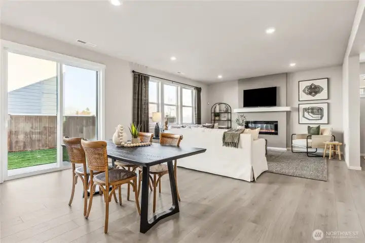 Inviting great room featuring an electric fireplace, large windows, sliding glass door to the backyard, and open dining area with tons of natural light. Photos are representative only and may display different color package and/or upgrades.