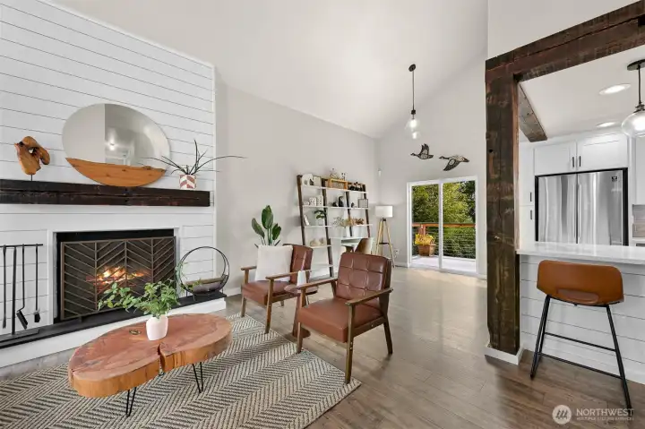 Vaulted ceilings, abundant natural light, and a cozy fireplace create an inviting gathering space that flows seamlessly into the kitchen and outdoor living areas.
